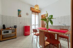 a kitchen with a table with chairs and a red refrigerator at The Domus vicino ad Alghero in Olmedo