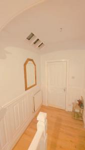 a white room with a mirror and a door at Ascot Room in Slough