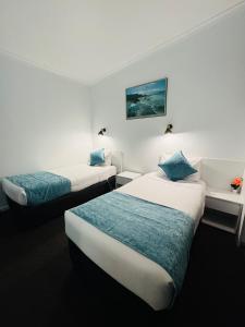 a hotel room with two beds with blue pillows at Bandicoot Motor Inn Hamilton in Hamilton