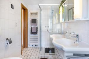 a white bathroom with two sinks and a shower at Ferienwohnung F Bolanz 1 in Auggen +23 photos