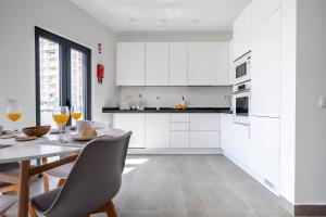 a kitchen with white cabinets and a table and chairs at Ptm riverview T2 luxe 2nd floor in Portimão +13 photos