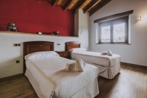 two beds in a room with a red wall at Fidalsa Rest Station in Burgos