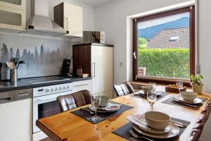 a kitchen with a wooden table and a large window at Am Sommerrain in Elzach