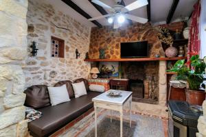 a living room with a couch and a stone wall at La Cuina De Paqui in Caserío Calandari