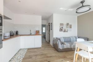 a white kitchen and living room with a couch at Melissa Apartment in Alaior