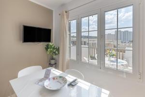 a white dining room with a table and a large window at Melissa Apartment in Alaior