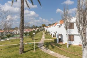 a white house with a palm tree at Melissa Apartment in Alaior