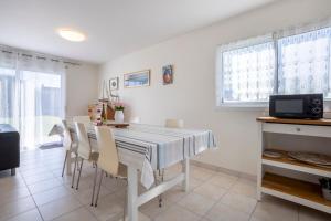 a white dining room with a table and chairs at La Pause Bigoudène in Penmarch