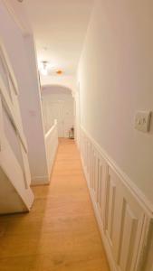 a hallway with white walls and a wooden floor at Pyramid Homes in Slough