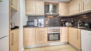 a kitchen with wooden cabinets and a microwave at Costacabana - Apartment Dali in Lloret de Mar