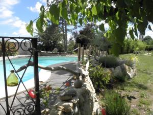 a pool with a wooden walkway next to a garden at L'arbre Du Magnan - Gîte En Ardèche in Chandolas