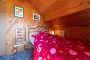 a bedroom with a red bed with a wooden ceiling at Chalet de Monique in Le Val-dʼAjol