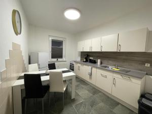 a kitchen with white cabinets and a table and chairs at Das grüne Haus in Finsterwalde