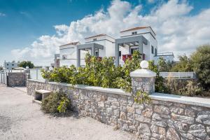 a large white house behind a stone wall at Blue Pearl in Lachania