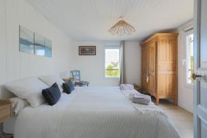 a bedroom with a large white bed with a window at Joisalig in Saint-Quay-Portrieux