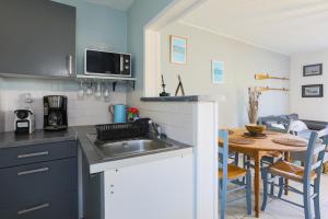a kitchen with a sink and a table with chairs at Joisalig in Saint-Quay-Portrieux