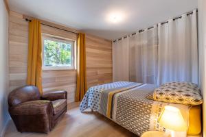 a bedroom with a bed and a chair and a window at Gite Familiale ty laouen in Sarzeau