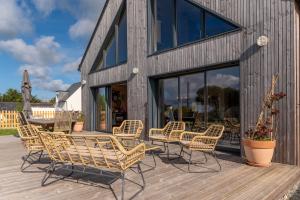 a group of chairs and tables on a wooden deck at Gite Familiale ty laouen in Sarzeau