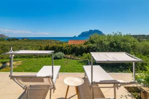 two chairs and tables on a patio with a view of the ocean at Villa Cactus, Costa Corallina in Olbia