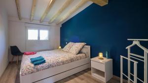 a bedroom with a bed and a blue wall at Maison - Chez Louisette in Espezel