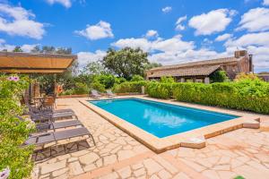 a swimming pool in a yard with chairs and a house at Son Galileu in Llucmajor