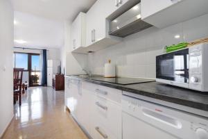 a kitchen with white cabinets and a black counter top at La Casa De Los Sueños in Corralejo