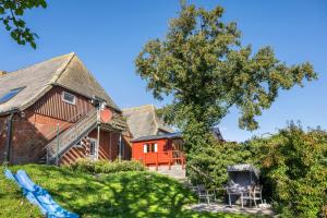 a house with a tree and chairs in the yard at Ferienhof Harrsen in Pellworm