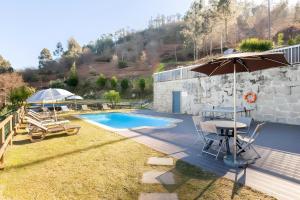 a patio with a table and an umbrella and a pool at Casa de Balinhas - Gerês in Ventosa