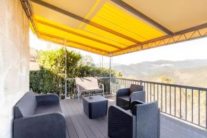 a deck with blue chairs and a yellow canopy at Casa de Balinhas - Gerês in Ventosa