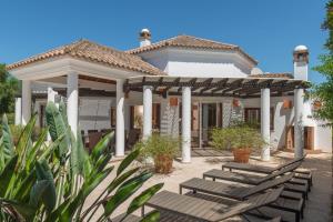 a white house with chairs and a pergola at Luxury Villa Malva in Benalup Casas Viejas