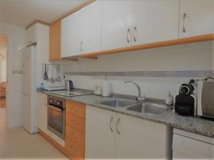 a kitchen with white cabinets and a sink at Ático en Jávea - Solo Familias 1813 in Platja de l'Arenal