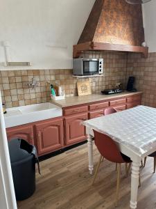 a kitchen with a table and a sink and a microwave at Appartement 16 colette in La Bourboule