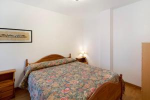 a bedroom with a bed with a floral bedspread at Residence Malibu Appartamento 9 in Falcade