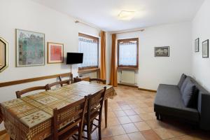 a dining room with a table and a couch at Residence Malibu Appartamento 9 in Falcade