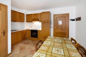 a kitchen with a table with chairs and a table and a tablecloth on at Residence Malibu Appartamento 9 in Falcade