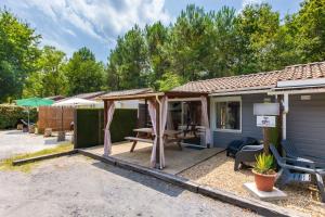 a house with a patio with a table and chairs at Chalet A Village Vacances in Gujan-Mestras
