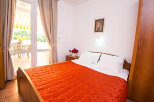 a bedroom with a large bed with an orange blanket at Apartments Sofija in Budva