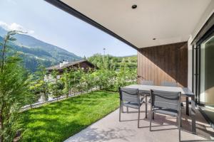 a dining table and chairs on a patio with a view of a garden at Aktiv Lodge Meran - Garden Two in San Martino