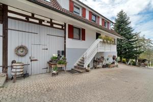 a white building with stairs and a porch with potted plants at Erlebnis-Bauernhof Scheunenglück in Oberkirch