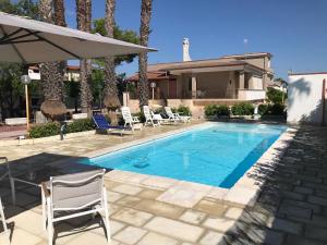 a swimming pool with chairs and a house at La Perla in Latiano