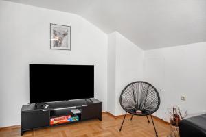 a living room with a flat screen tv and a chair at Ferienwohnung Carlina in Pfronten