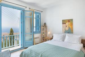 a bedroom with a bed and a large window at Efrossyni House in Ioulis