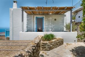 a home with a stone retaining wall and a pergola at Efrossyni House in Ioulis