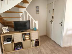 a living room with a tv and a staircase at Maison De Plage Le Cocon Pirouais in Pirou