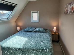 a bedroom with a bed with a blue comforter and two lamps at Maison De Plage Le Cocon Pirouais in Pirou