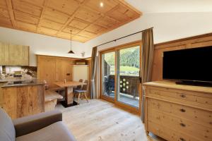 a living room with a television and a kitchen with a table at Steineggerhof in Valle Di Casies