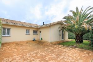 a house with a palm tree in front of it at Villa Melchivany - Nature et Océan in Messanges