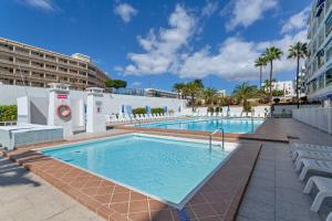 a swimming pool with chairs and a resort at Apartamento Yumbo Maspalomas in Maspalomas