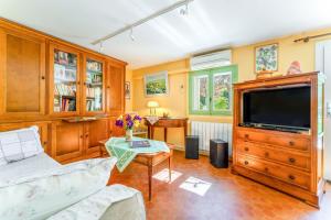 a living room with a tv and a couch at La Tonnelle, clim, jardin in Malaucène