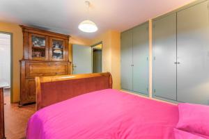 a bedroom with a pink bed and a cabinet at La Tonnelle, clim, jardin in Malaucène